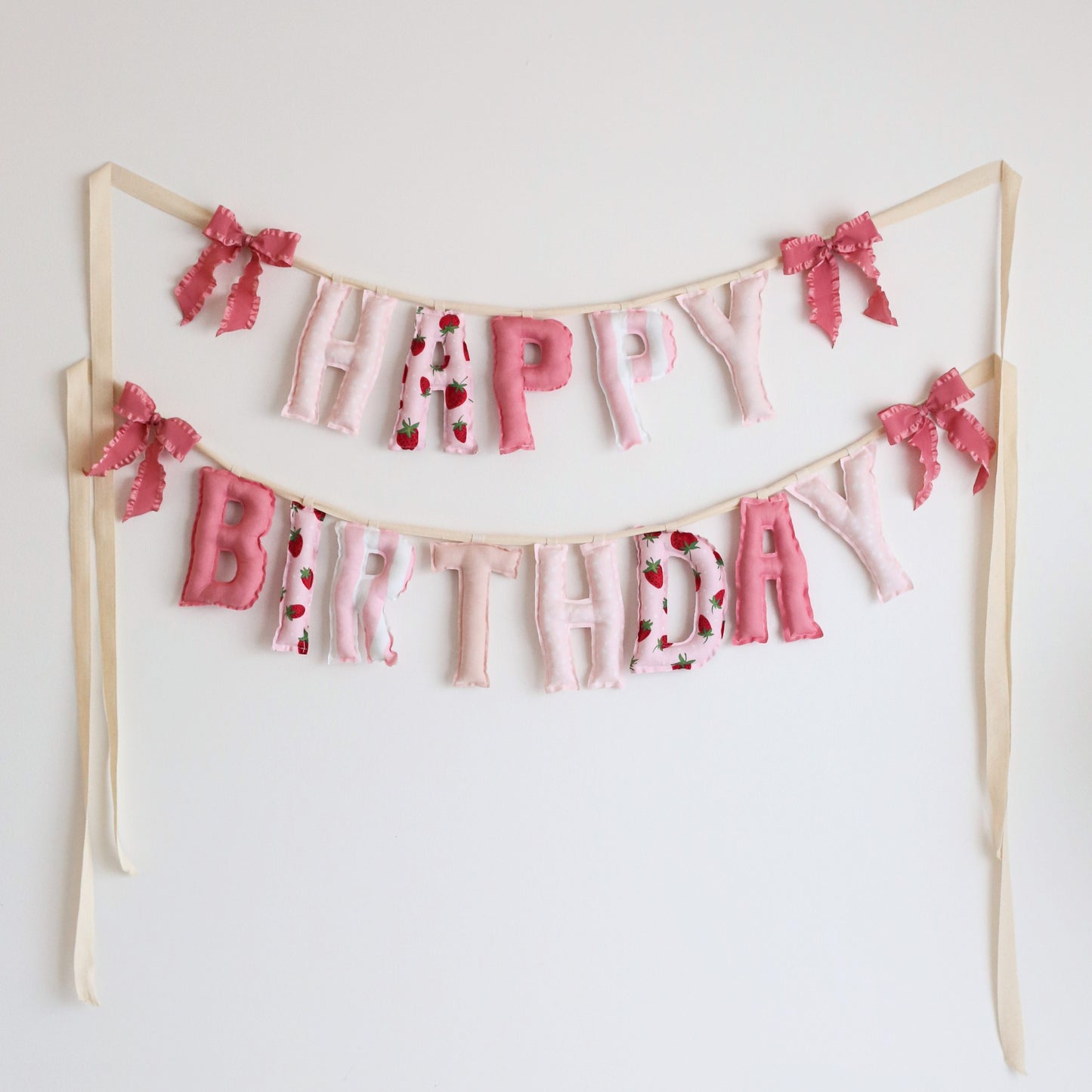 Berry Sweet handmade ‘Happy Birthday’ garland by Social Heirloom – soft pink, strawberry print, and polka dot cotton letters with ruffle pink bows, perfect for strawberry birthday parties, nursery decor, or berry sweet first birthdays