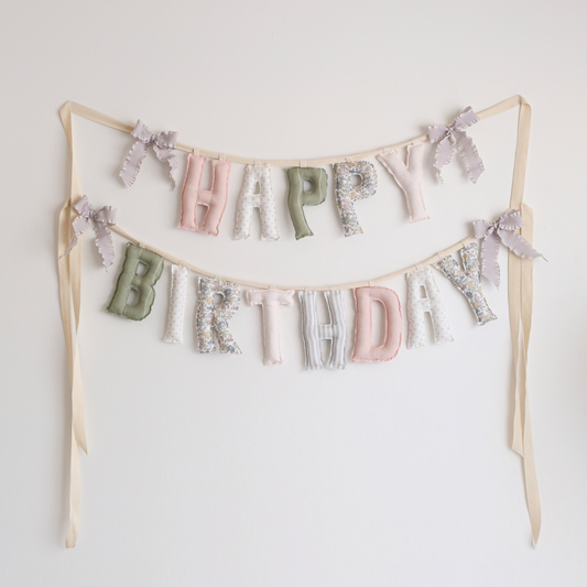 Blush & Olive handmade ‘Happy Birthday’ garland by Social Heirloom – soft pinks, sage greens, florals, and neutrals with grey ruffle bows, perfect for first birthdays, nurseries, and timeless heirloom celebrations.