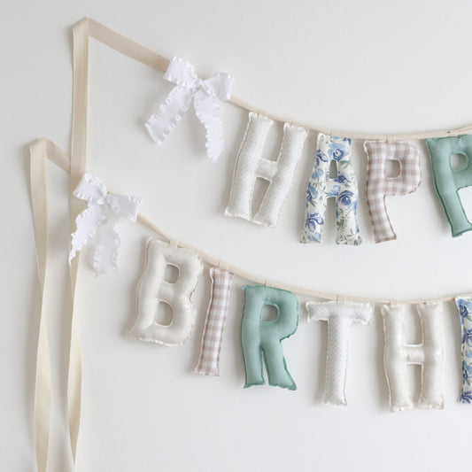 Close-up of Garden Window handmade birthday garland by Social Heirloom – detailed view of soft cotton letters in floral, gingham, and muted tones with ruffle bows, ideal for first birthdays or nursery decor