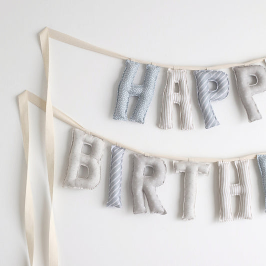 Close-up of Salt and Sky handmade birthday garland by Social Heirloom – soft cotton letters in blue, gray, and stripe patterns for heirloom birthday decor and nursery styling