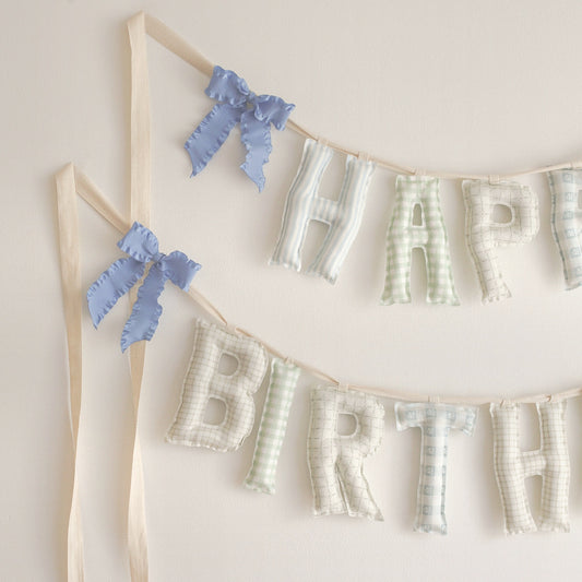 Close up of the Huckleberry Happy Birthday garland, soft filled fabric letters in soft blue stripes, sage gingham and sweet little checks in blue, green and oat