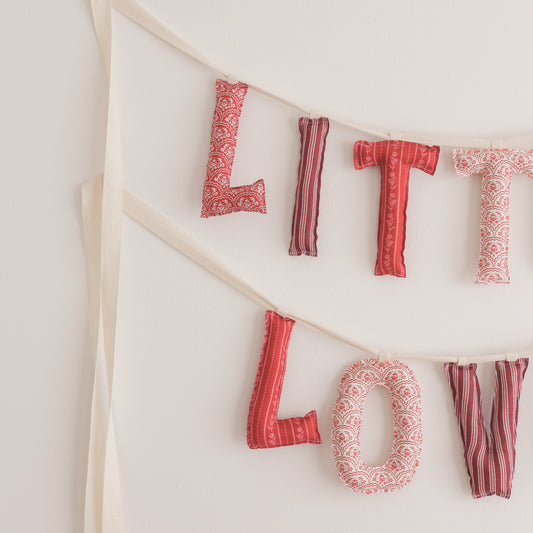 Fabric letter banner spelling 'LITTLE LOVE' on a white background