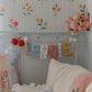 Big Day Parade personalized name garland spelling LENNIE hanging in a floral nursery, handmade fabric letters in colorful florals, mustard, berry dots, gingham and candy stripes by Social Heirloom