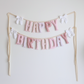 Lace & Petals handmade ‘Happy Birthday’ garland by Social Heirloom – soft pinks, dusty rose, and bow-print fabrics with white ruffle bows, perfect for first birthdays, nurseries, or delicate, heirloom celebrations
