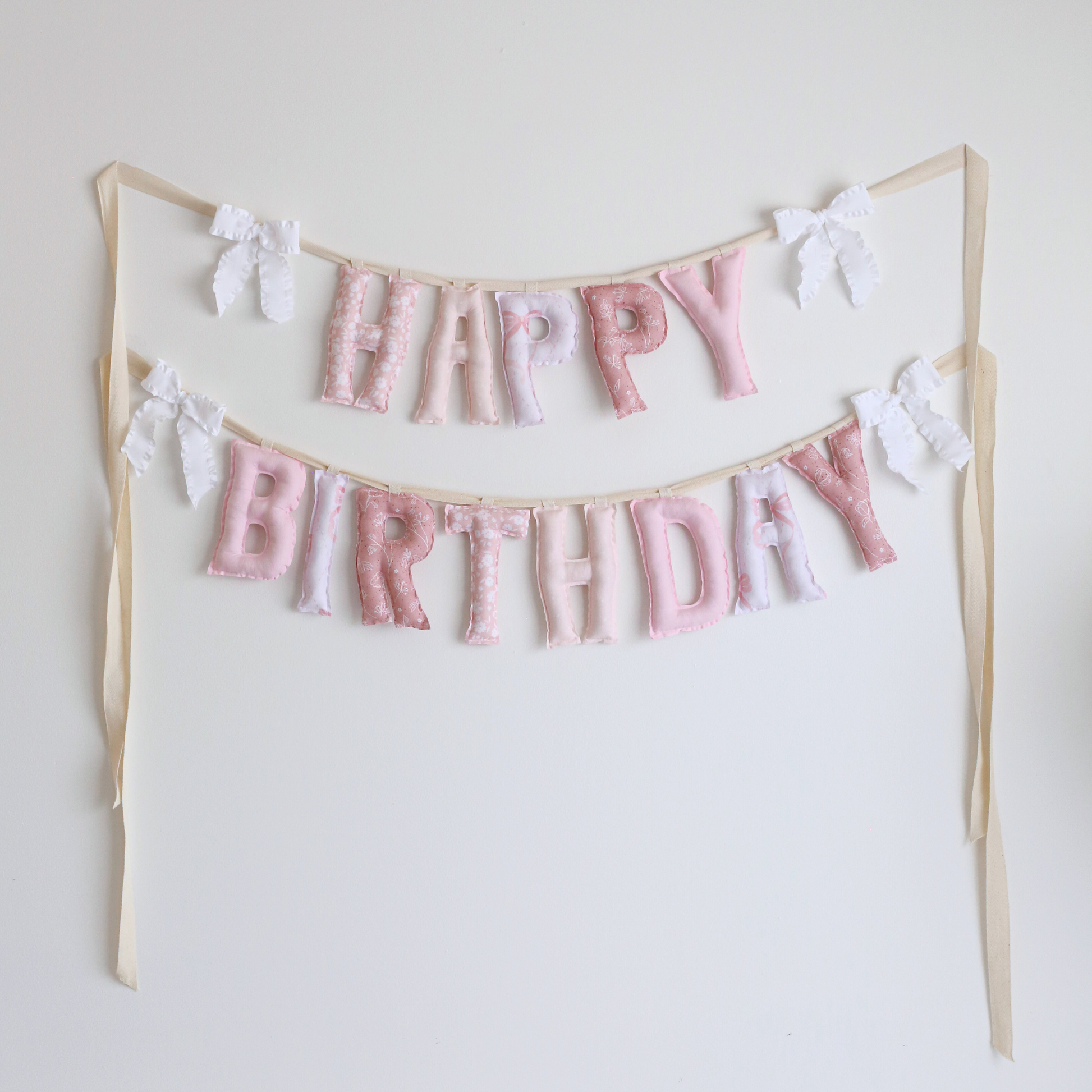 Lace & Petals handmade ‘Happy Birthday’ garland by Social Heirloom – soft pinks, dusty rose, and bow-print fabrics with white ruffle bows, perfect for first birthdays, nurseries, or delicate, heirloom celebrations