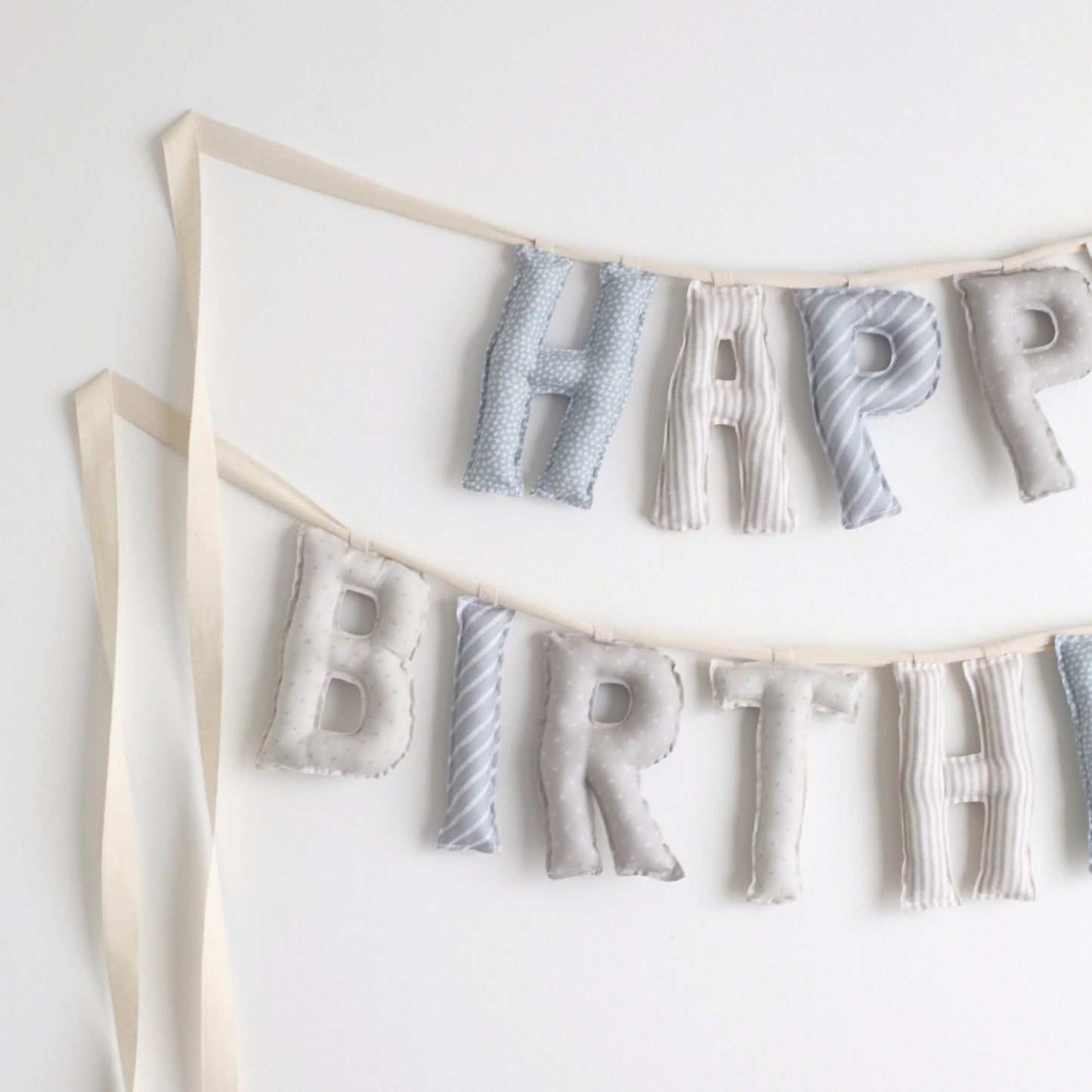 Close-up of Salt and Sky handmade birthday garland by Social Heirloom – soft cotton letters in blue, gray, and stripe patterns for heirloom birthday decor and nursery styling
