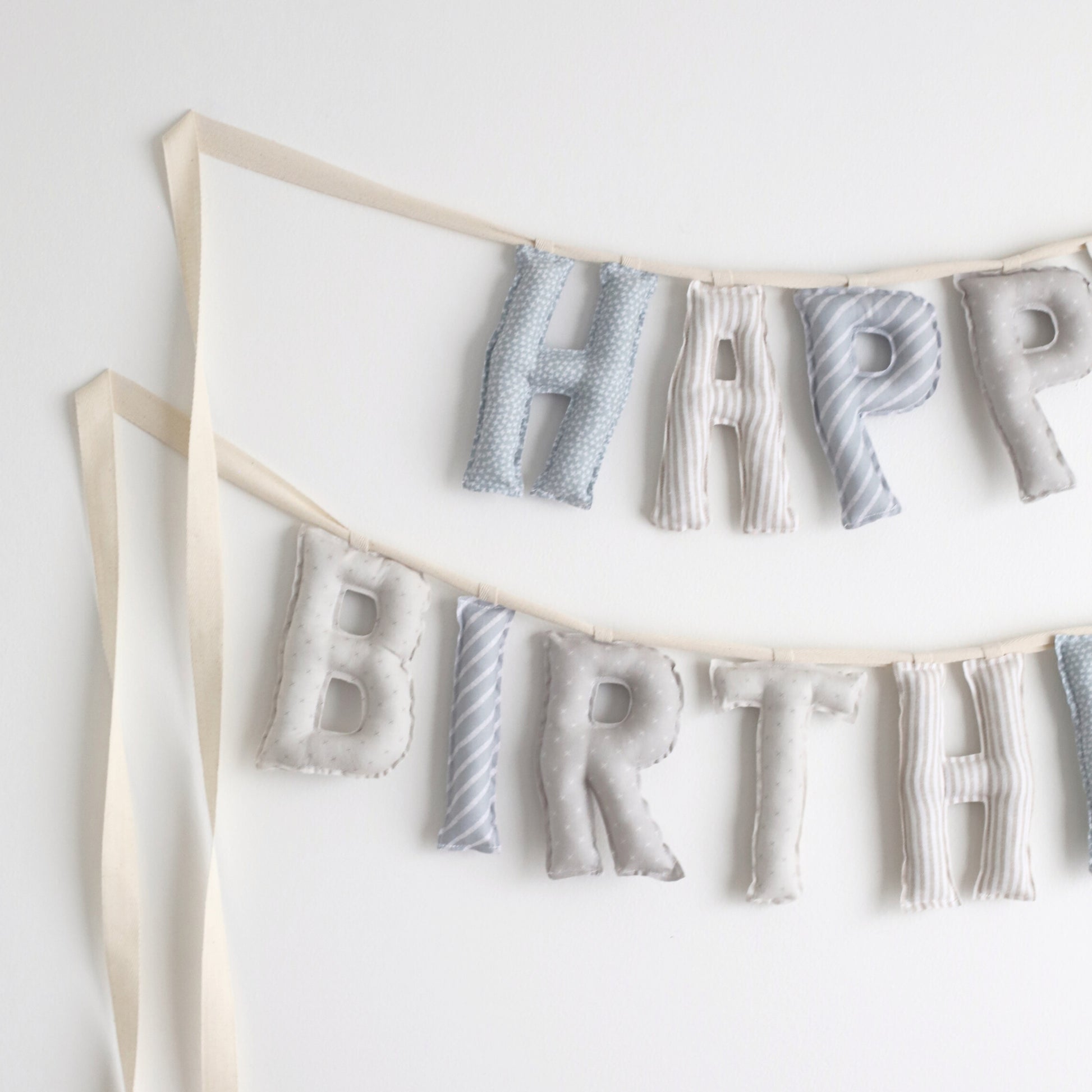Close-up of Salt and Sky handmade birthday garland by Social Heirloom – soft cotton letters in blue, gray, and stripe patterns for heirloom birthday decor and nursery styling
