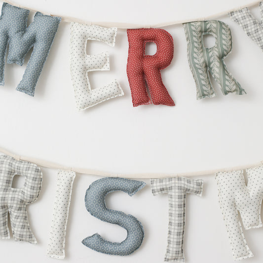 Fabric letter banner spelling 'Merry Christmas' on a white background