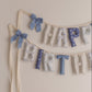 Decorative 'Happy Birthday' banner with ribbons on a beige background