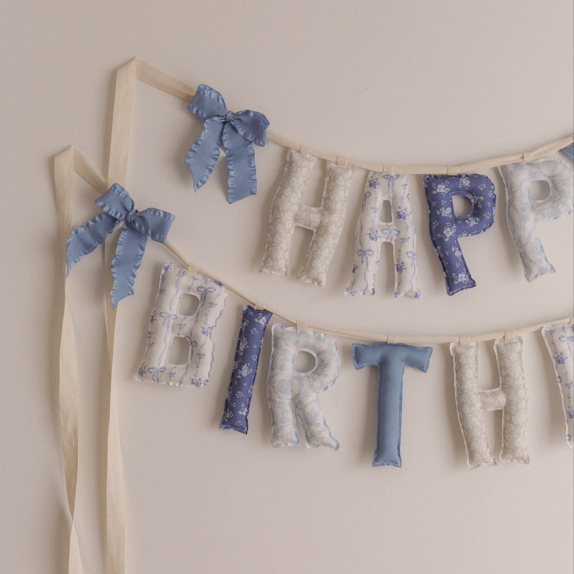 Decorative 'Happy Birthday' banner with ribbons on a beige background