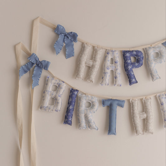 Decorative 'Happy Birthday' banner with ribbons on a beige background