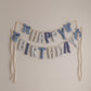Decorative 'Happy Birthday' banner with blue and white elements on a plain wall.