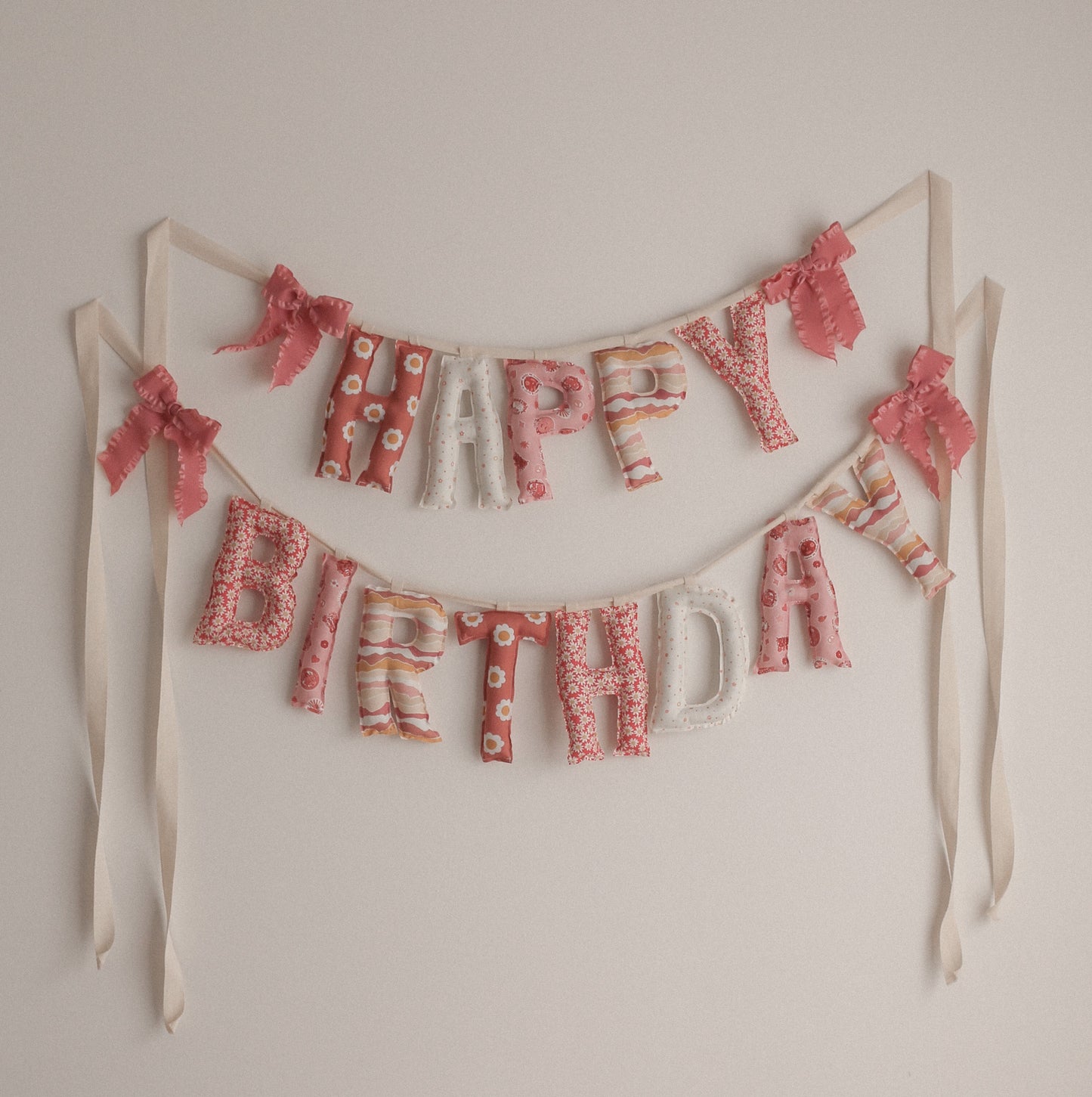 Fabric Happy Birthday banner with pink 70s groovy print on a white wall