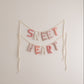 Decorative banner with 'SWEET HEART' text on a plain wall