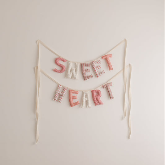 Decorative banner with 'SWEET HEART' text on a plain wall