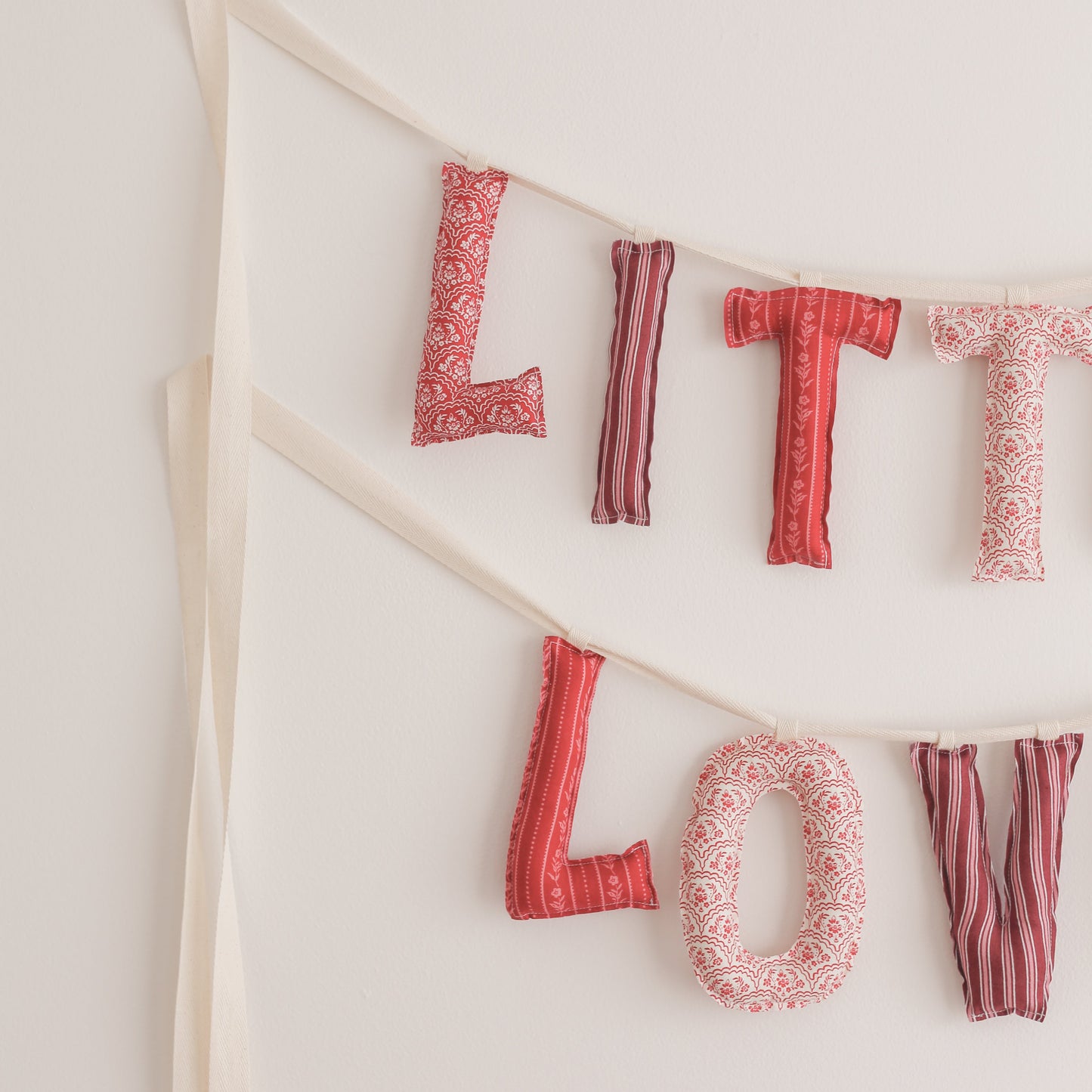 Fabric letter banner spelling 'LITTLE LOVE' on a white background
