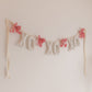 Decorative banner with 'XO' letters and pink flowers on a plain background