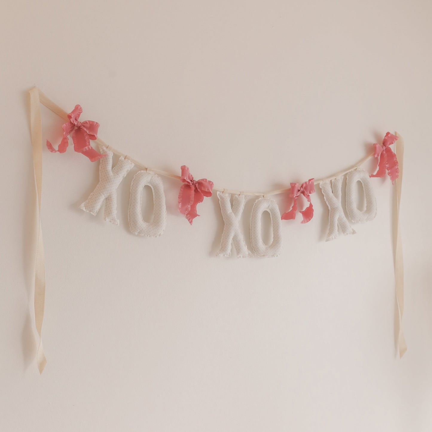 Decorative banner with 'XO' letters and pink flowers on a plain background
