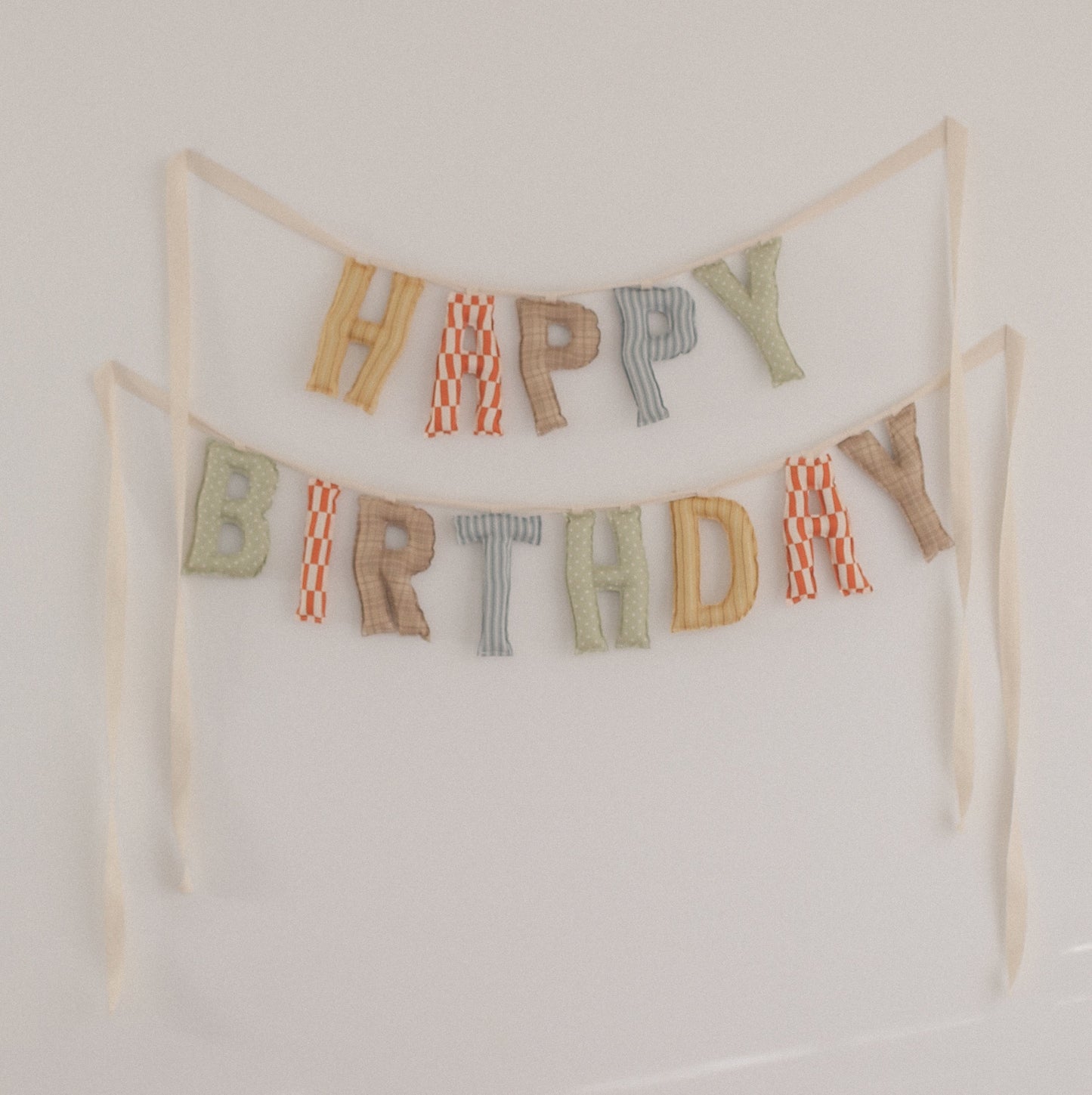 Colorful 'Happy Birthday' banner hanging on a white wall