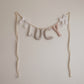 Little Hearth House personalized name garland spelling LUCY, handmade fabric letters in blush, a small floral, sage and taupe gingham by Social Heirloom