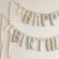 Close up of the Sunday Cottage Happy Birthday garland, soft filled fabric letters in tiny florals across taupe, cream, dusty rose, sage and blush