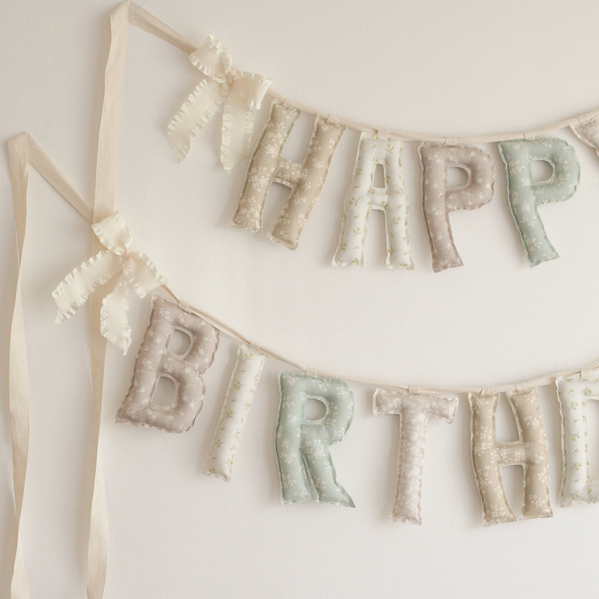 Close up of the Sunday Cottage Happy Birthday garland, soft filled fabric letters in tiny florals across taupe, cream, dusty rose, sage and blush